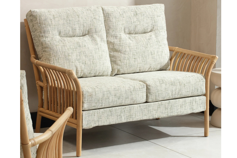 Two-seater sofa with wicker armrests in a room setting