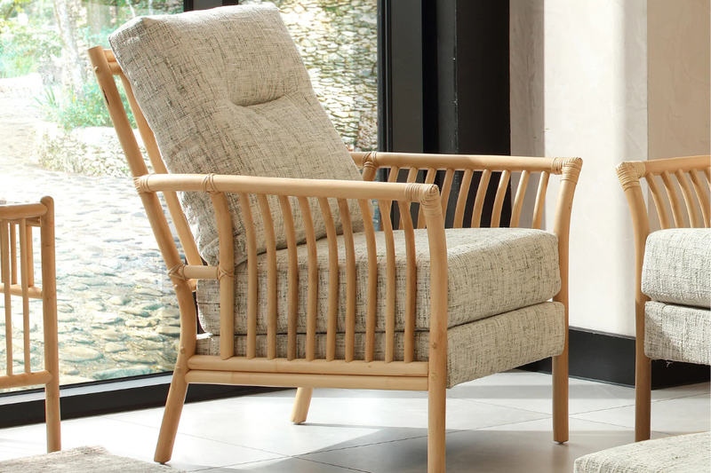 Beige armchair with wooden frame in a room with large windows
